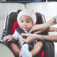 A baby getting into car sear