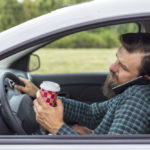 Driver holding coffee and talking on cell