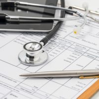 Stethoscope on medical billing statement on table, all text is a Stethoscope on medical billing statement on table, all text is a